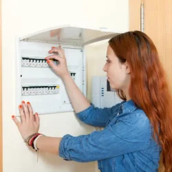 mujer viendo un cuadro eléctrico en una vivienda